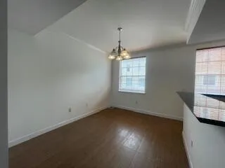 an empty room with wooden floor chandelier and windows