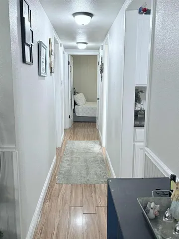 a view of a hallway with wooden floor and living room