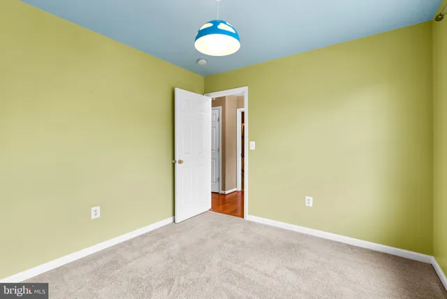 an empty room with a chandelier fan and a large window