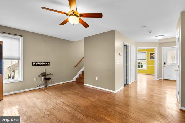 a view of empty room with wooden floor and fan