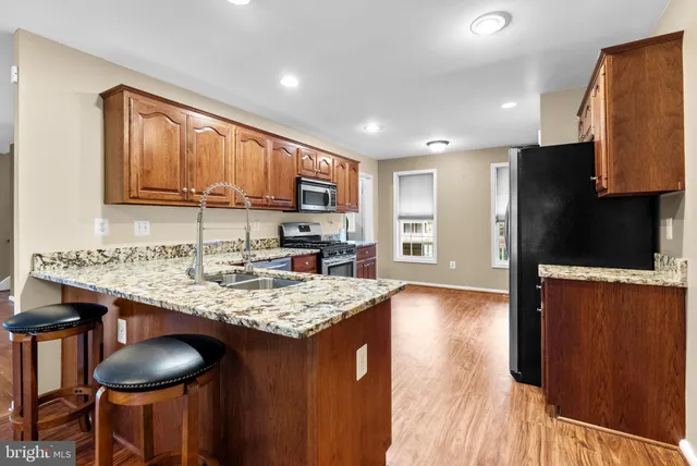 a kitchen with stainless steel appliances granite countertop a table chairs sink and cabinets