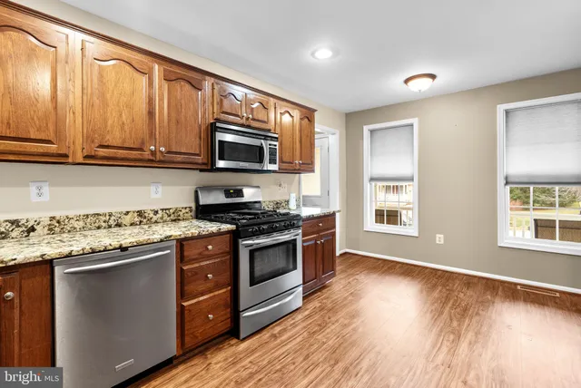 a kitchen with stainless steel appliances granite countertop a stove a sink and a microwave