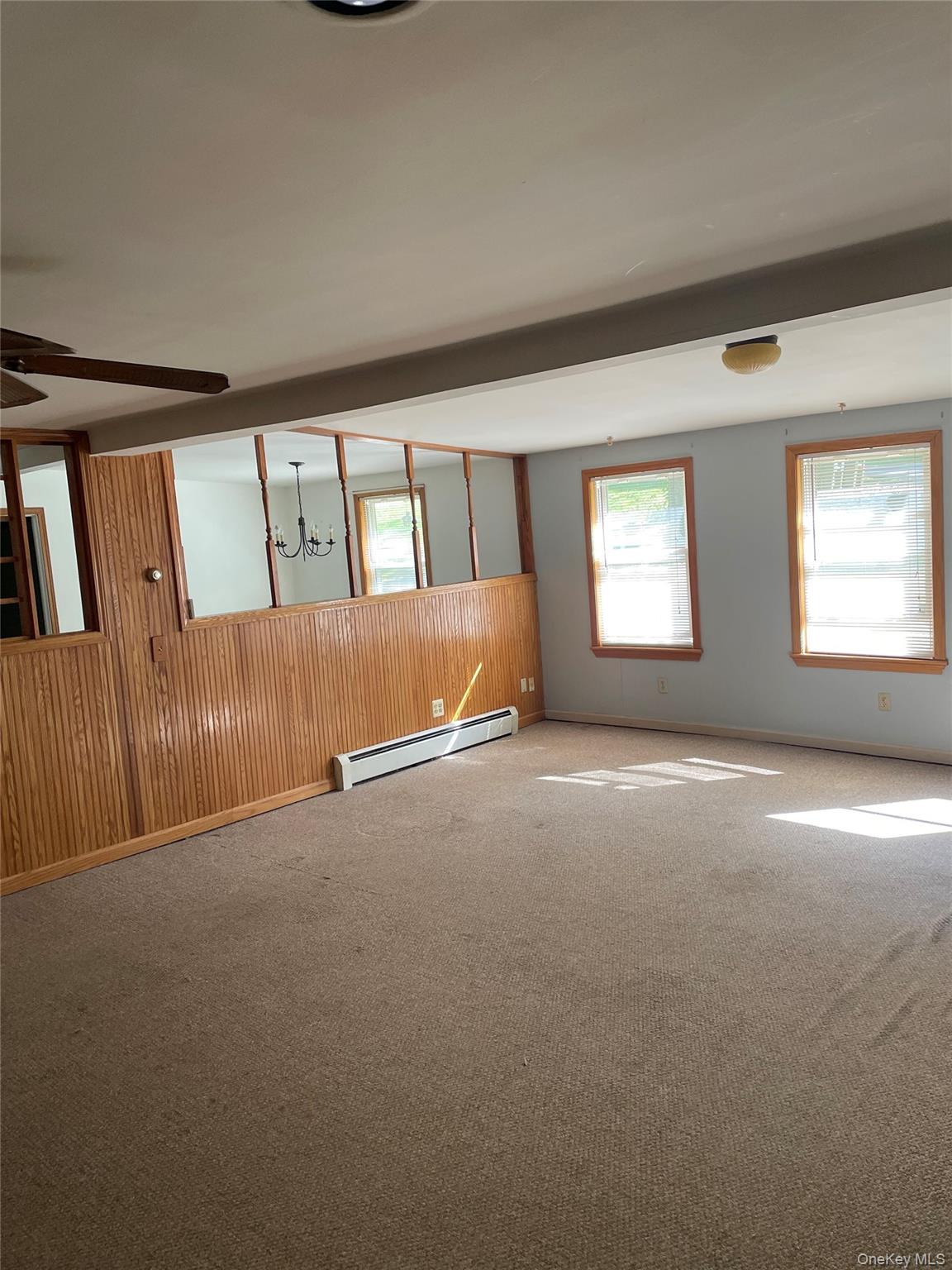 67 Bethlehem Road New Windsor, NY 12553 - Photo 13 of 19 Carpeted spare room with a chandelier, baseboard heating, wooden walls, and ceiling fan