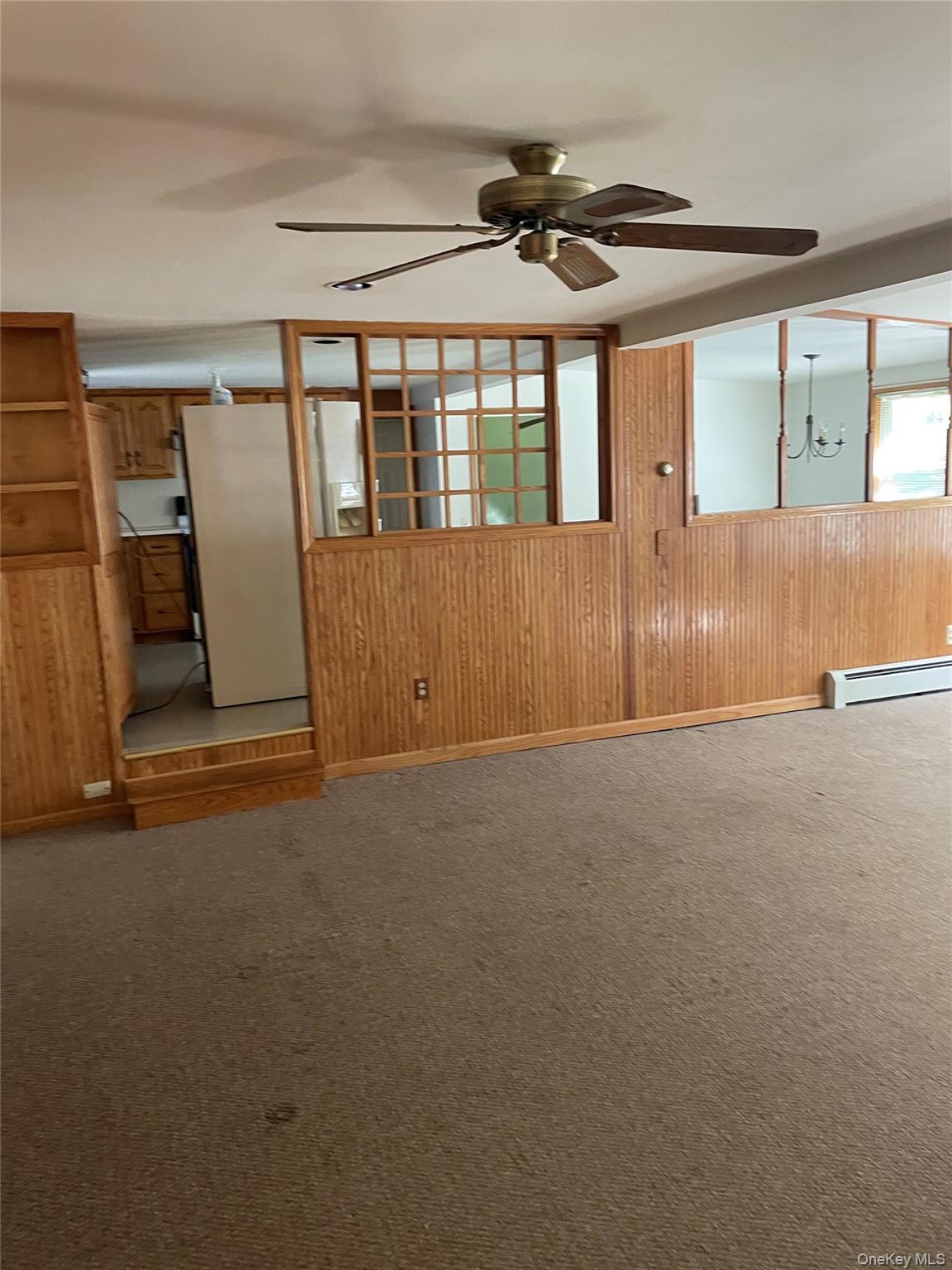 67 Bethlehem Road New Windsor, NY 12553 - Photo 16 of 19 Carpeted empty room featuring wooden walls, a ceiling fan, a baseboard heating unit, and a chandelier