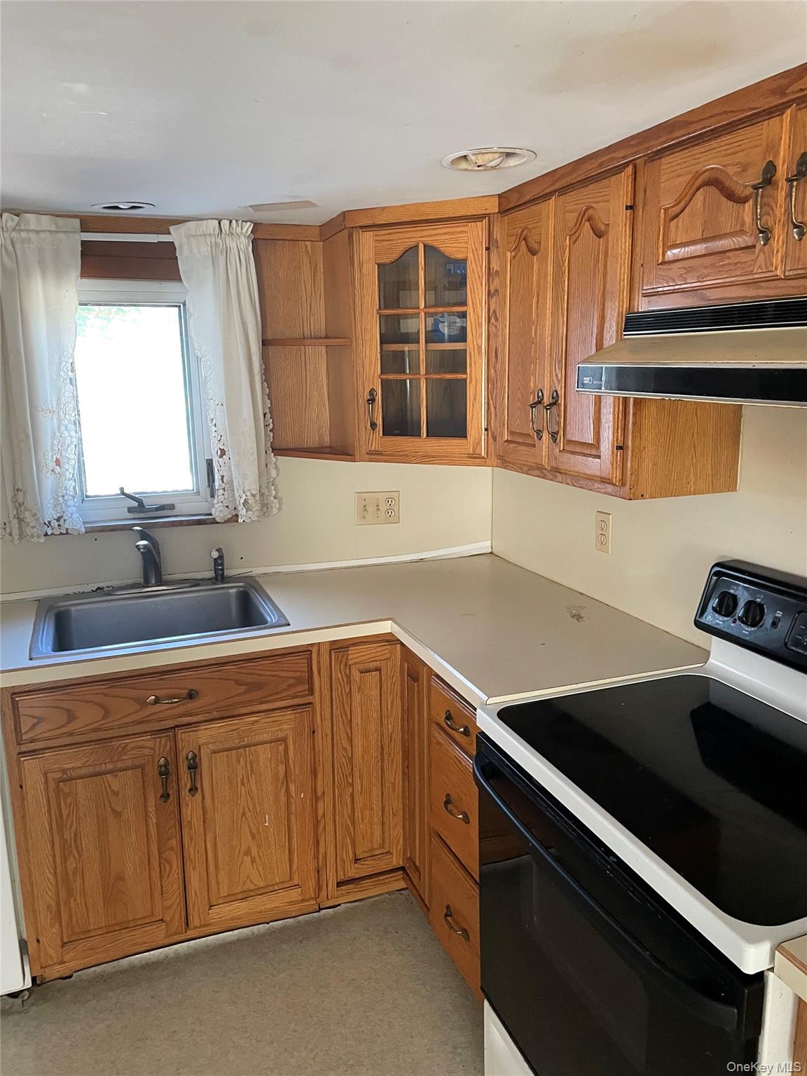 67 Bethlehem Road New Windsor, NY 12553 - Photo 3 of 19 Kitchen featuring range with electric cooktop, brown cabinets, under cabinet range hood, light countertops, and glass insert cabinets