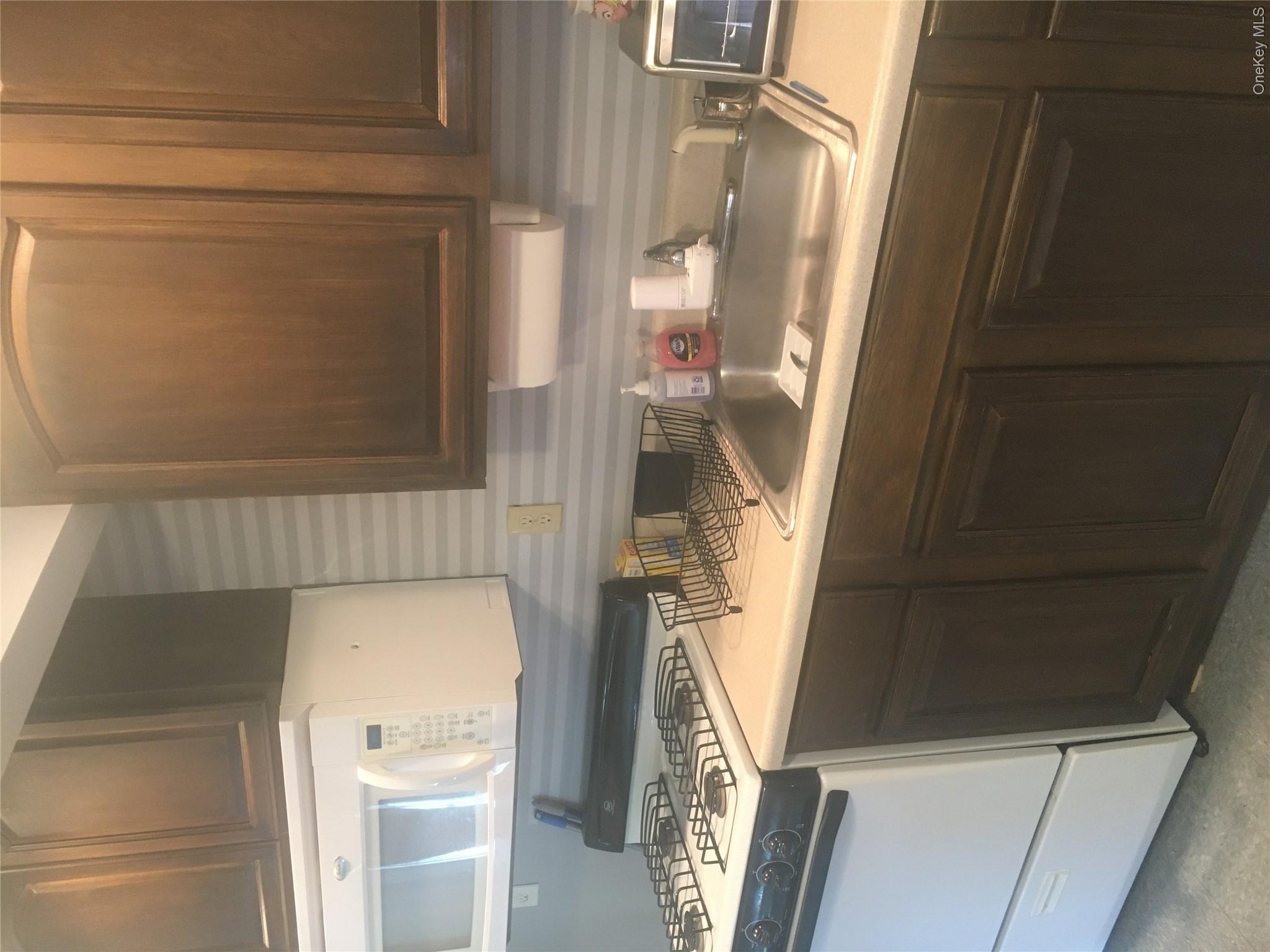 67 Bethlehem Road New Windsor, NY 12553 - Photo 4 of 19 Kitchen with a sink, range, dark brown cabinetry, light countertops, and wallpapered walls