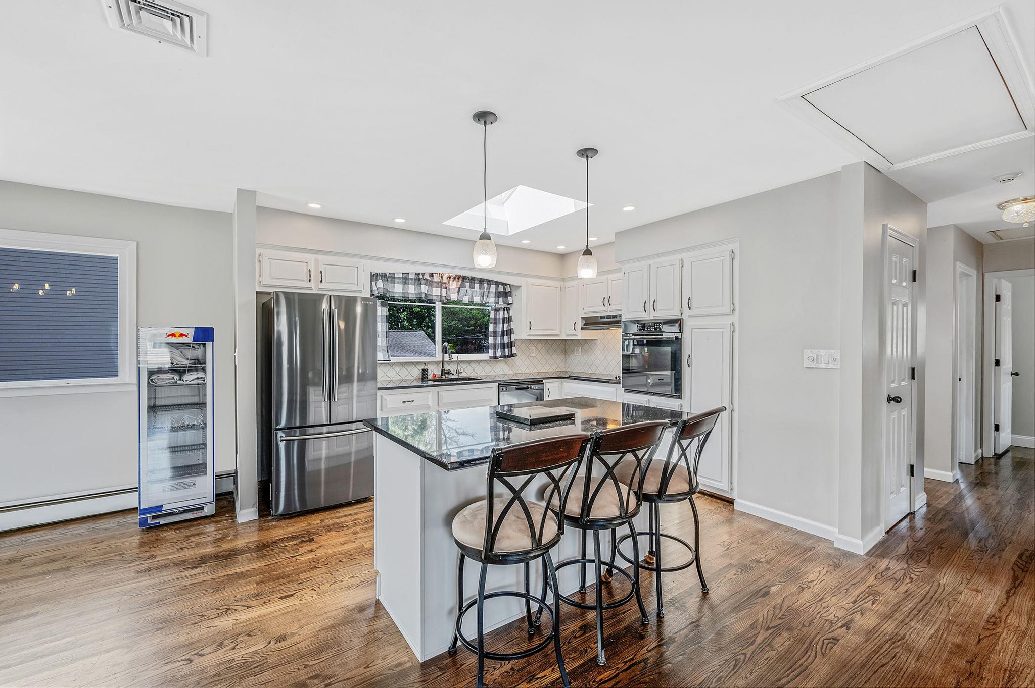 6 Holly Road Oakdale, NY 11769 - Photo 18 of 34 a kitchen with stainless steel appliances a dining table chairs and wooden floor