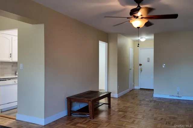 a view of a livingroom with a chandelier fan and wooden floor