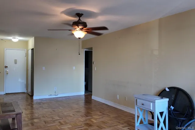 a view of a room with a chandelier fan and wooden floor