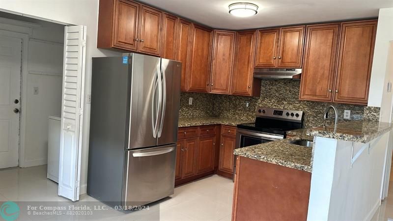 a kitchen with granite countertop stainless steel appliances a refrigerator a stove a sink and cabinets