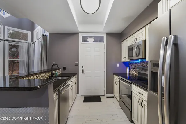 a kitchen with stainless steel appliances granite countertop a refrigerator a stove and a sink with wooden floor