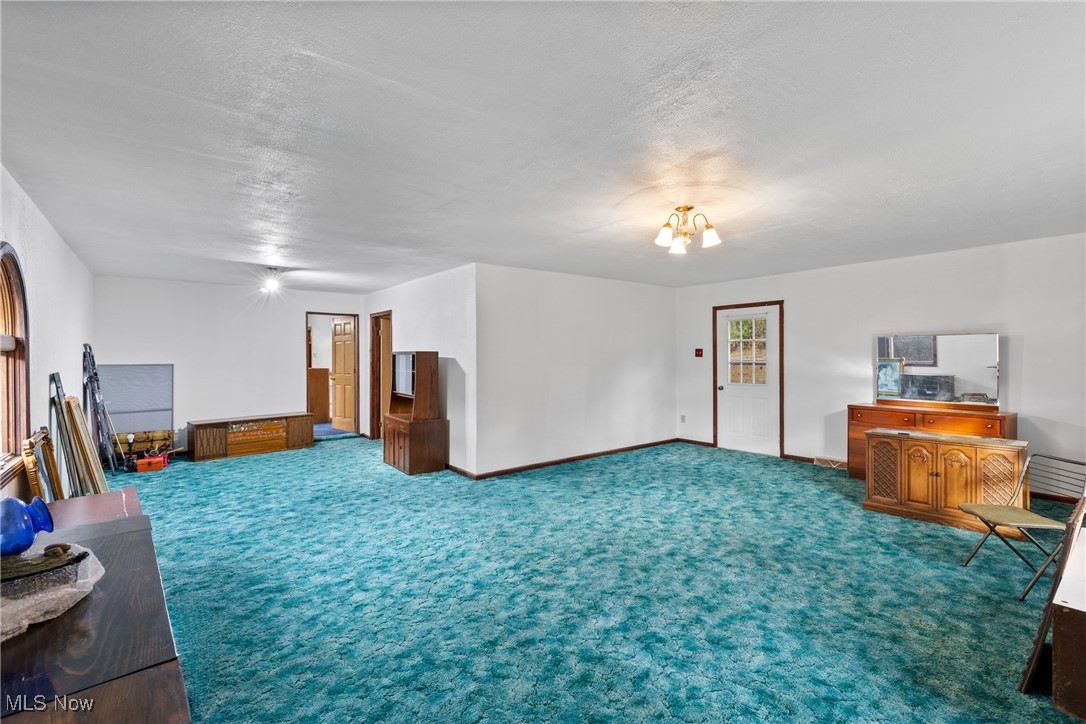 102 Potrock Road Wellsburg, WV 26070 - Photo 18 of 42 Living area with carpet, a textured ceiling, and a chandelier