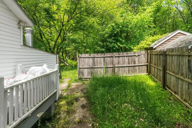 a view of backyard with green space and wooden fence