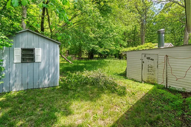 a view of a backyard with large trees and wooden fence