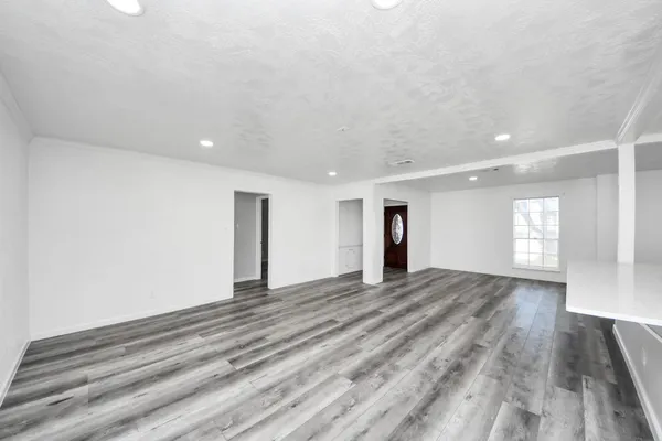 a view of an empty room with window and wooden floor