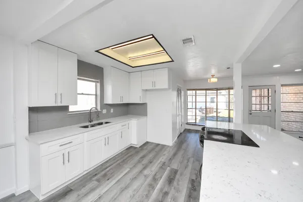 a kitchen with a sink dishwasher a stove and white cabinets with wooden floor