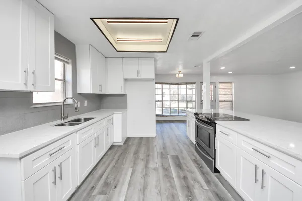 a kitchen with granite countertop a sink cabinets wooden floor and stainless steel appliances