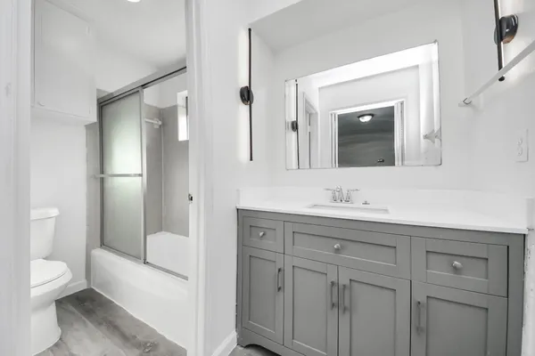 a bathroom with a toilet a sink a mirror a bathtub and vanity