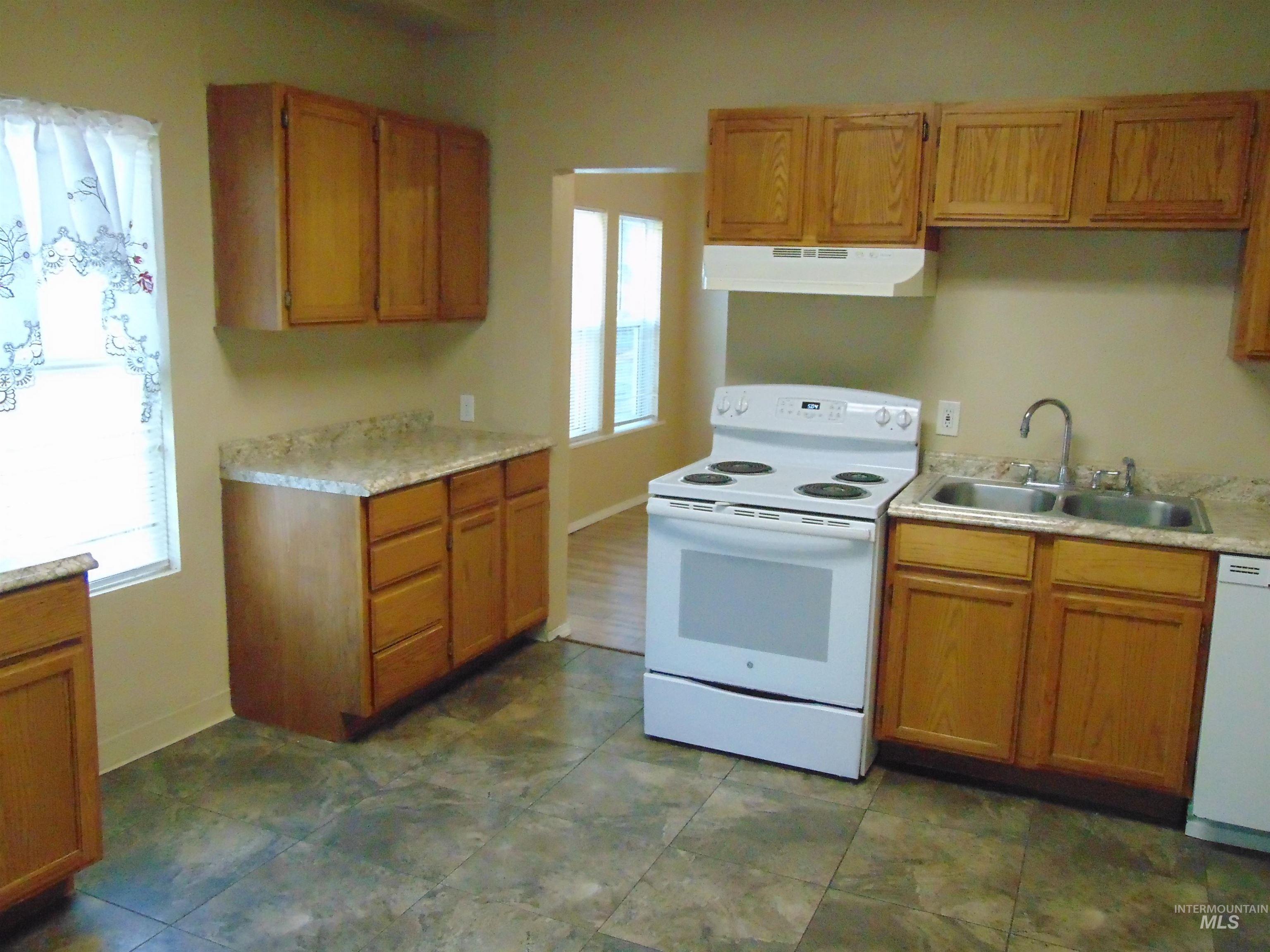 1825 7th Avenue Lewiston, ID 83501 - Photo 11 of 26 Kitchen with white appliances, light countertops, under cabinet range hood, and brown cabinets