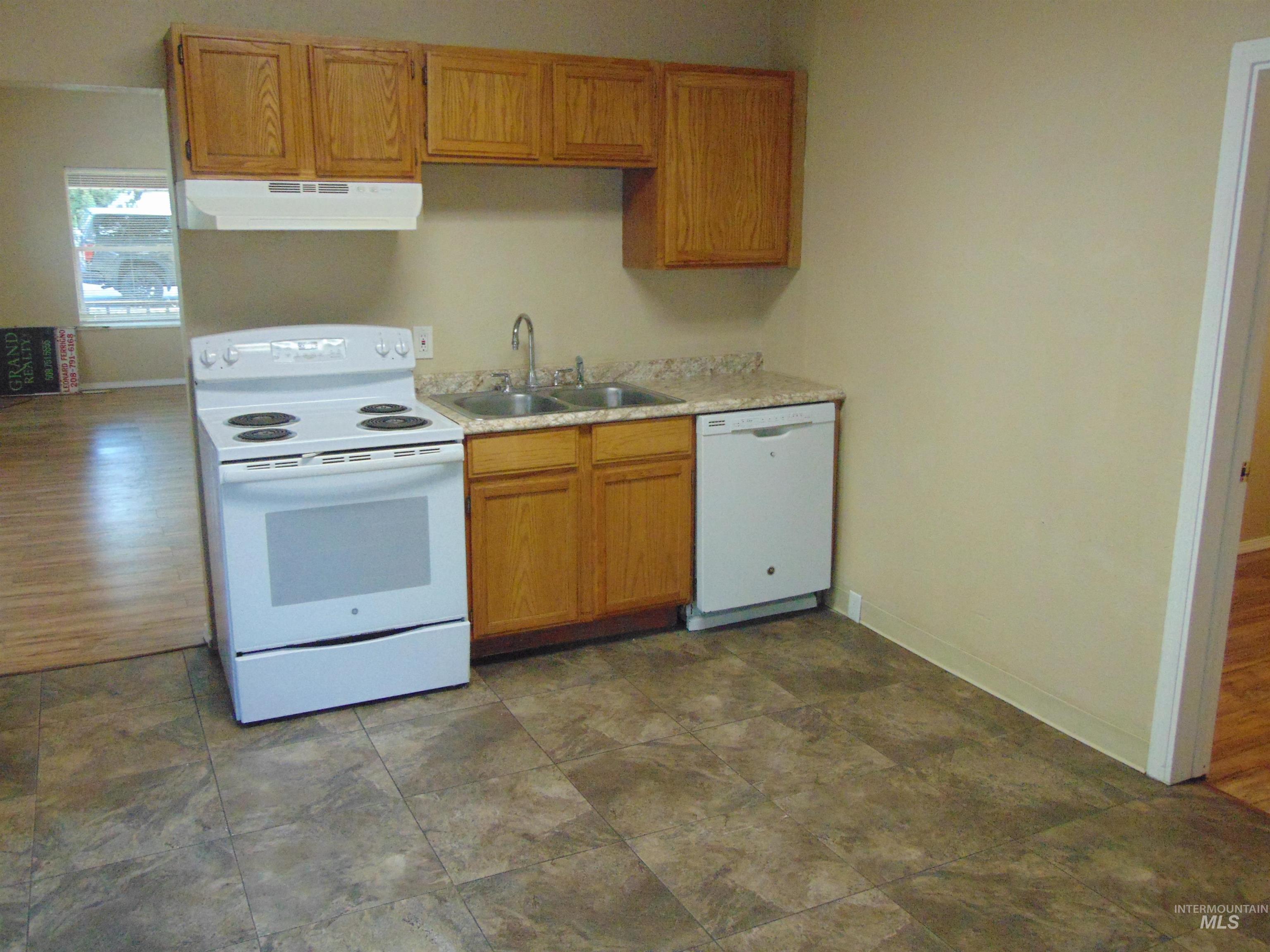 1825 7th Avenue Lewiston, ID 83501 - Photo 12 of 26 Kitchen with white appliances, light countertops, brown cabinetry, and under cabinet range hood