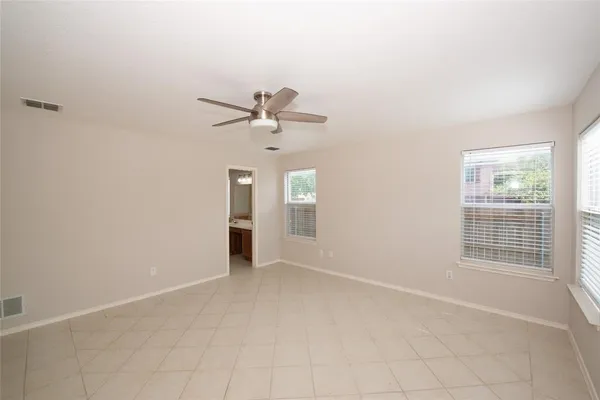 an empty room with windows and fan