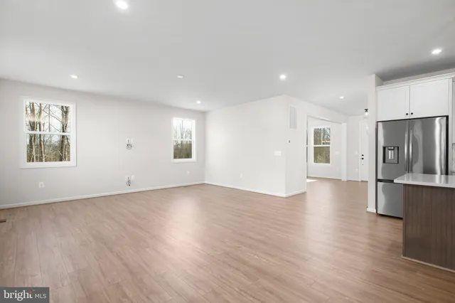 a large kitchen with stainless steel appliances granite countertop a refrigerator a sink a stove and white cabinets with wooden floor