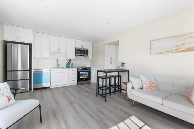 a living room with stainless steel appliances furniture and a kitchen view