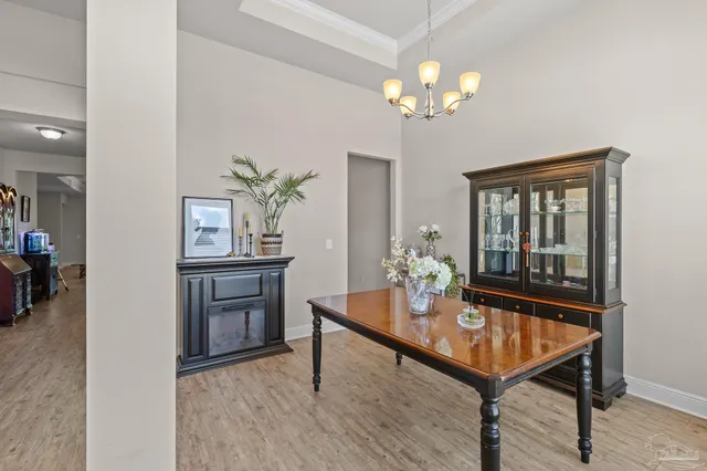 a dining room with wooden floor a chandelier a wooden table and chairs