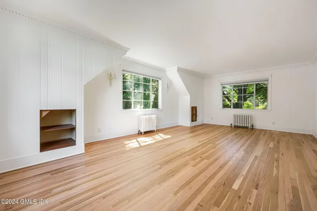 an empty room with windows and fireplace