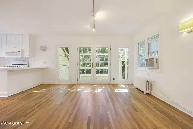 a view of an empty room with a window and wooden floor