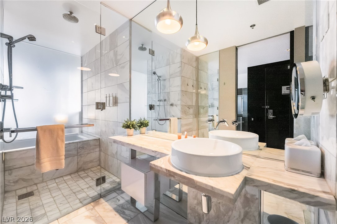 4381 West Flamingo Road, Unit 18305 Las Vegas, NV 89103 - Photo 8 of 19 Marble finishes elevate this well-appointed bathroom featuring dual vessel sinks and a spacious walk-in shower.