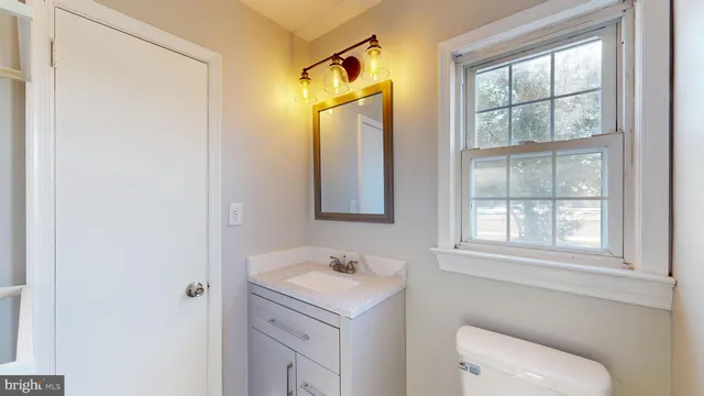 a bathroom with a granite countertop sink toilet and a mirror