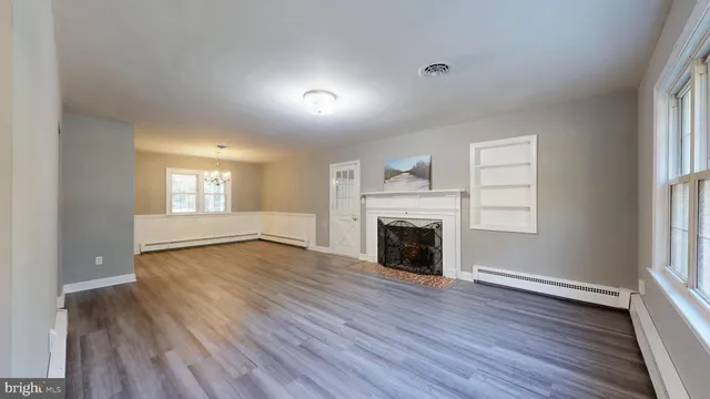 an empty room with wooden floor fireplace and windows