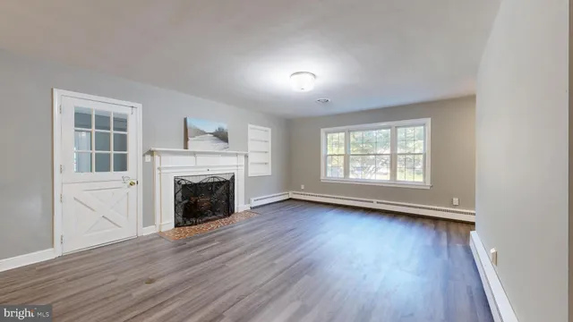 an empty room with wooden floor fireplace and windows