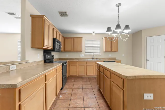 a kitchen with a sink dishwasher a stove top oven a kitchen island and chairs with wooden floor