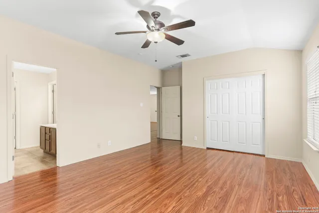 an empty room with wooden floor and a ceiling fan