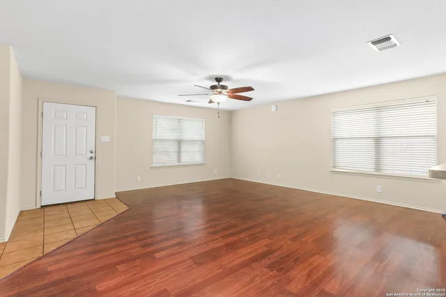an empty room with wooden floor and windows