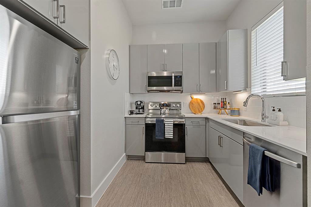 579 Lloyd's Road, Unit 821A Little Elm, TX 75068 - Photo 8 of 25 a kitchen with stainless steel appliances granite countertop a refrigerator a stove a sink and a microwave