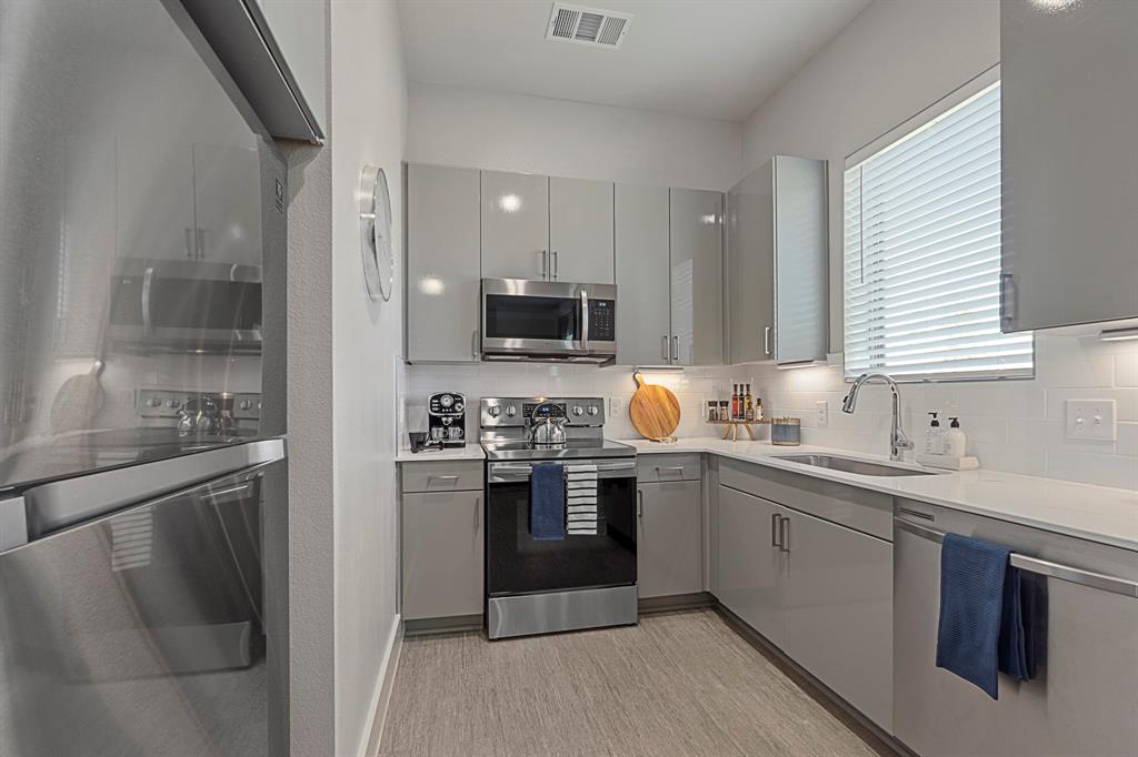 579 Lloyd's Road, Unit 821A Little Elm, TX 75068 - Photo 9 of 25 a kitchen with stainless steel appliances granite countertop a sink stove and refrigerator