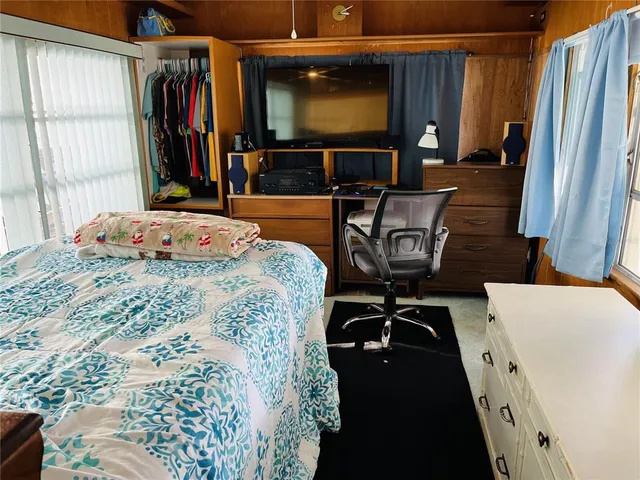 a bedroom with a bed and a flat tv screen on dresser