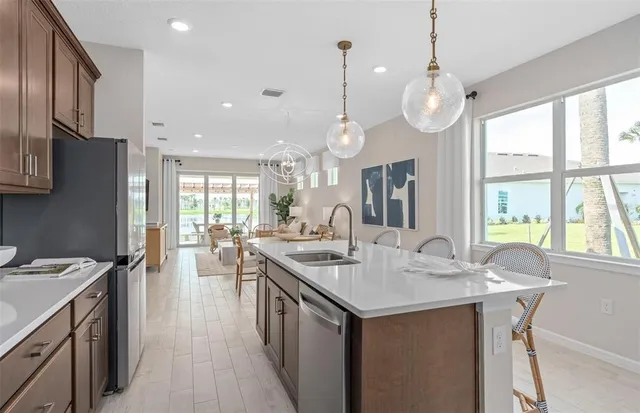 a kitchen with stainless steel appliances granite countertop a refrigerator a stove a sink dishwasher a refrigerator with a dining table and chairs