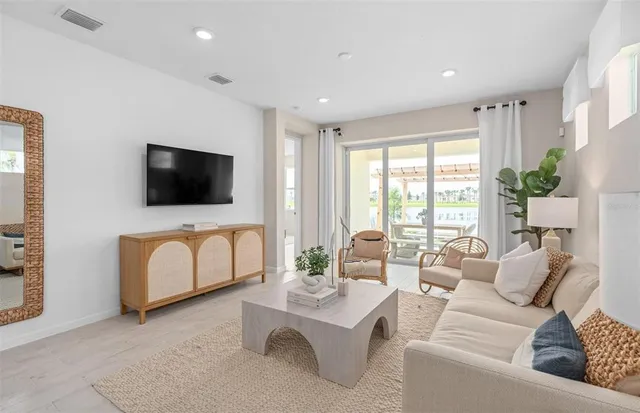 a living room with furniture kitchen view and a flat screen tv