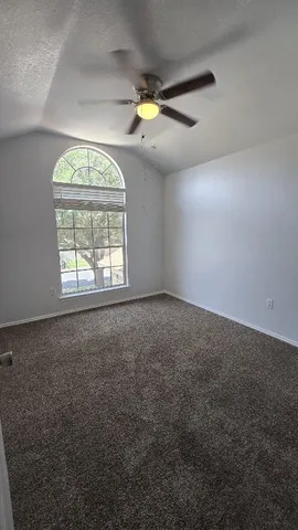 an empty room with windows and a ceiling fan
