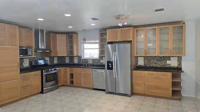 a kitchen with stainless steel appliances granite countertop a refrigerator and a stove top oven