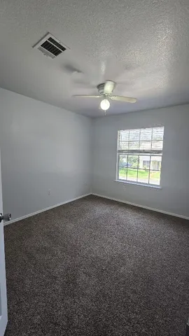 an empty room with windows and fan