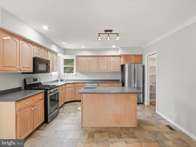 a kitchen with stainless steel appliances granite countertop a sink stove microwave and refrigerator