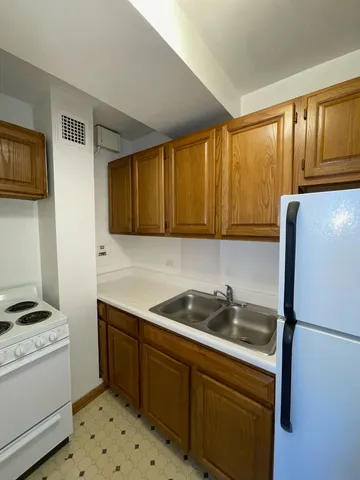 a kitchen with stainless steel appliances a refrigerator a sink and white cabinets