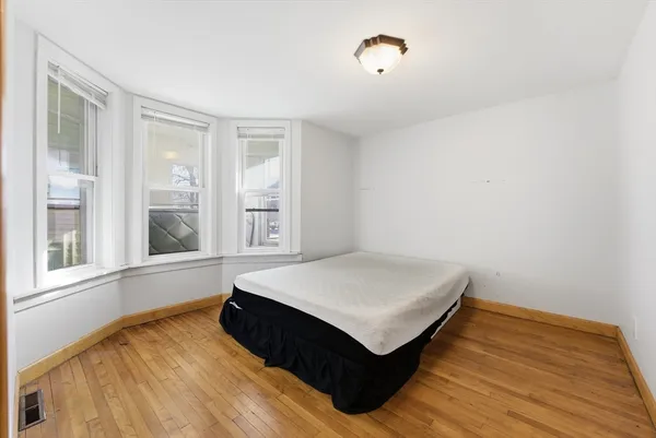 a spacious bedroom with a bed and wooden floor