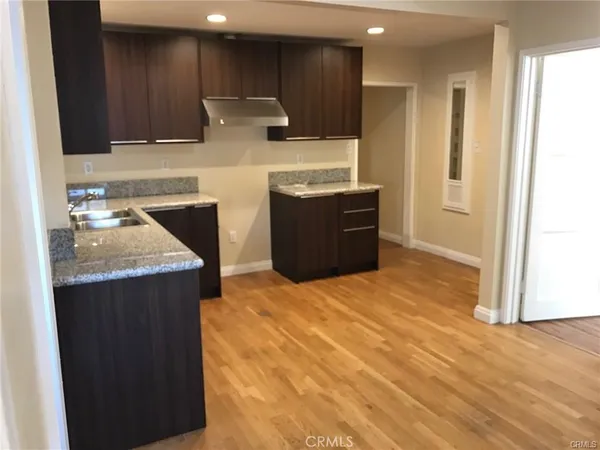 a kitchen with stainless steel appliances granite countertop a refrigerator a sink dishwasher and wooden cabinets with wooden floor