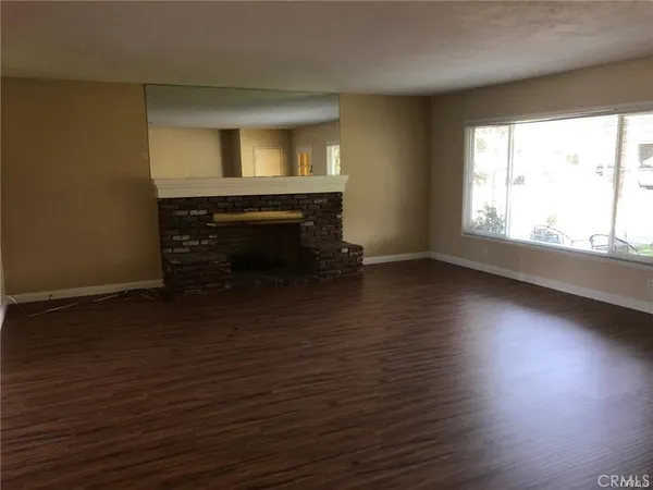 an empty room with wooden floor a fireplace and windows